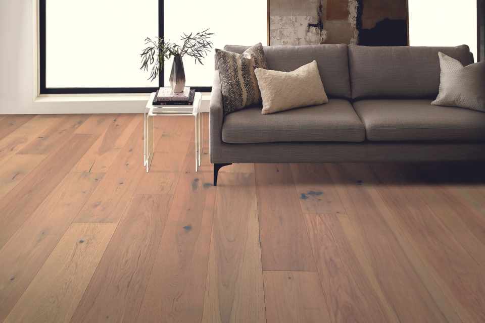 engineered hardwood flooring in modern industrial living room with gray couch and greenery